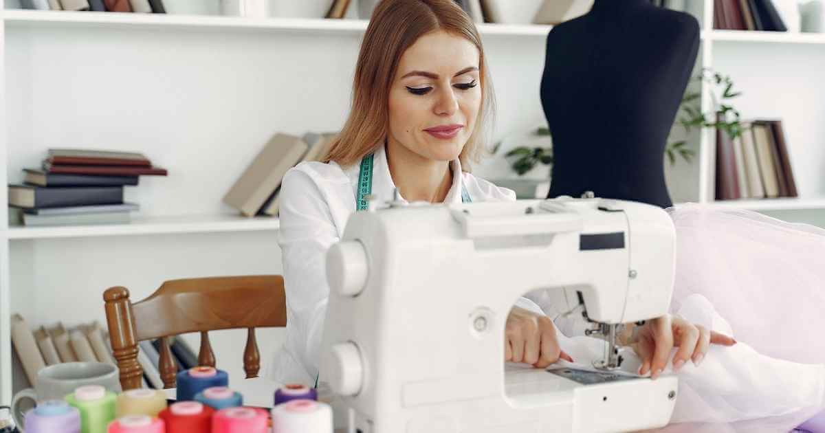 A woman sitting at a table using a sewing machine.