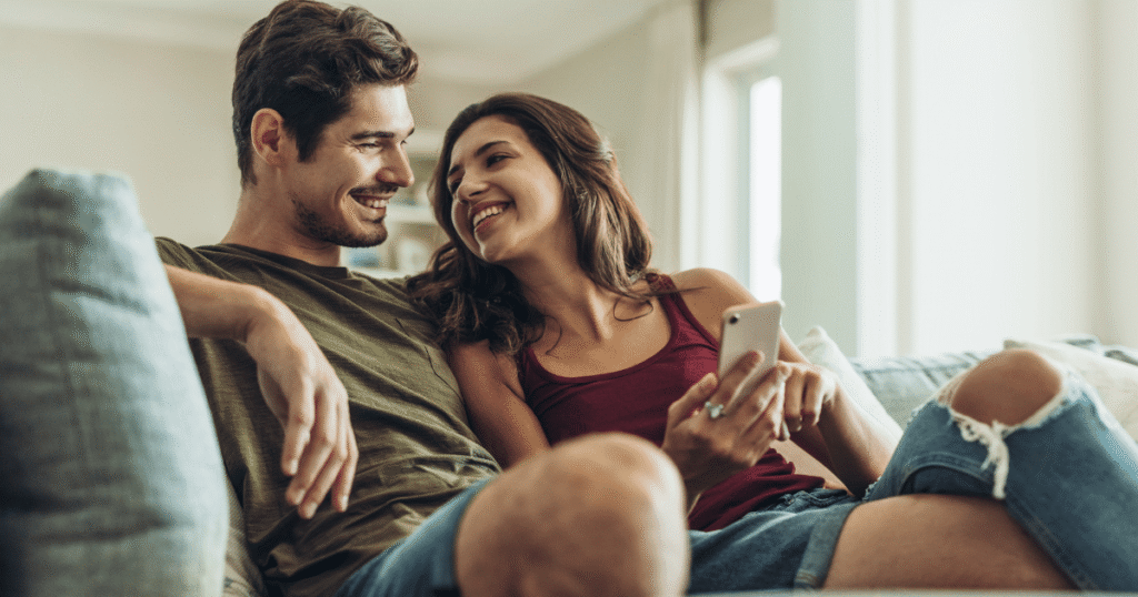 Happy couple sitting together on couch and smiling. Credit @jacoblund