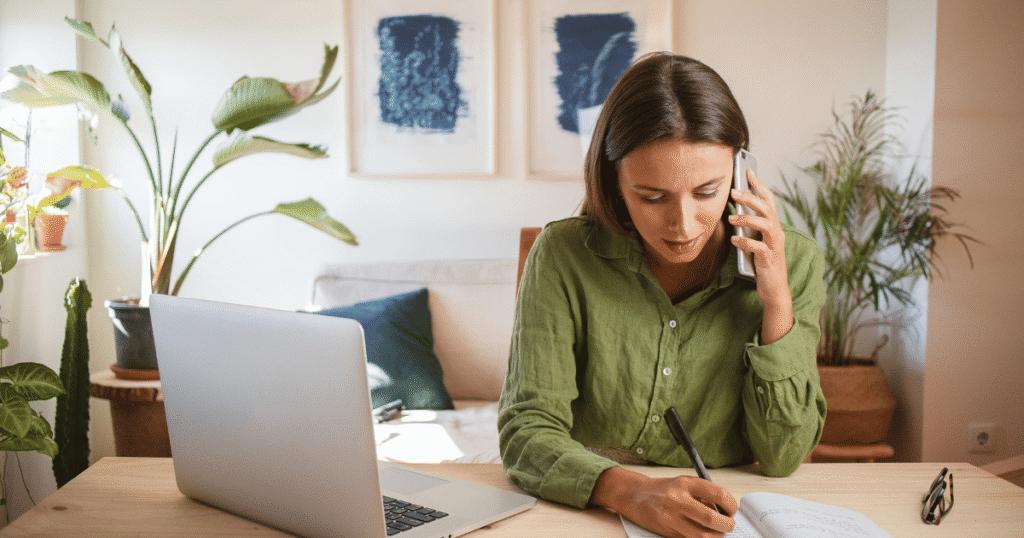 Woman talking on phone with open laptop on desk. Credit @lais-schulz