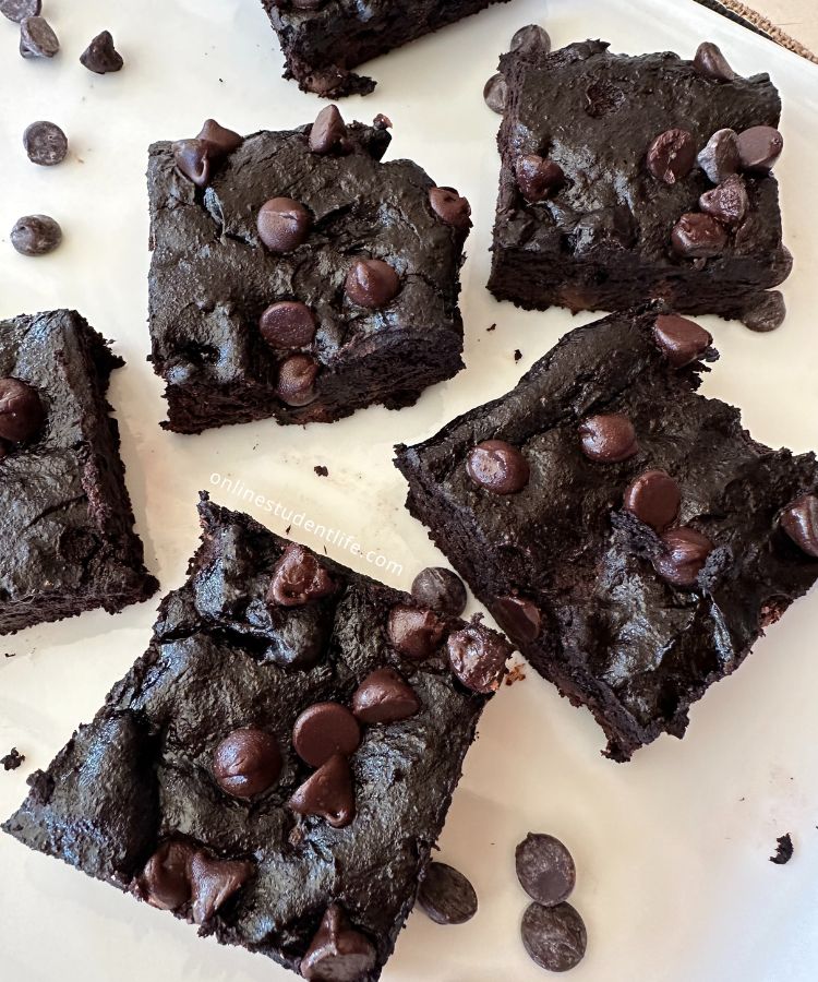 Avocado brownies on a white plate with chocolate chips scattered around