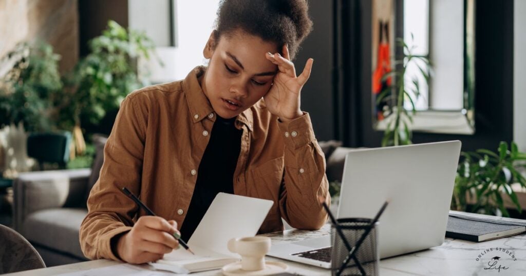 Woman writing in a notebook while thinking.