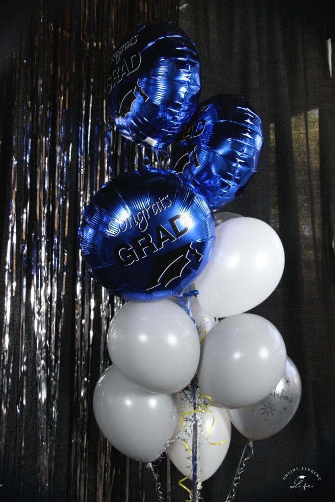 White, grey and blue helium balloons with the words "congrats grad" printed on them.