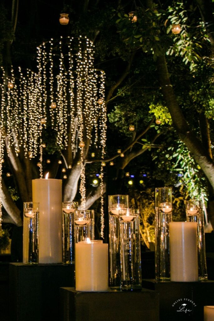 An outdoor space lit up at night with circular hanging fairy light strings and candles.