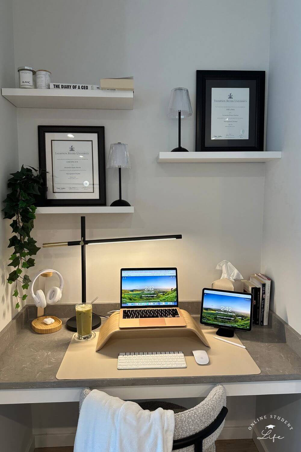 A online student desk setup with a laptop, ipad and framed degrees.