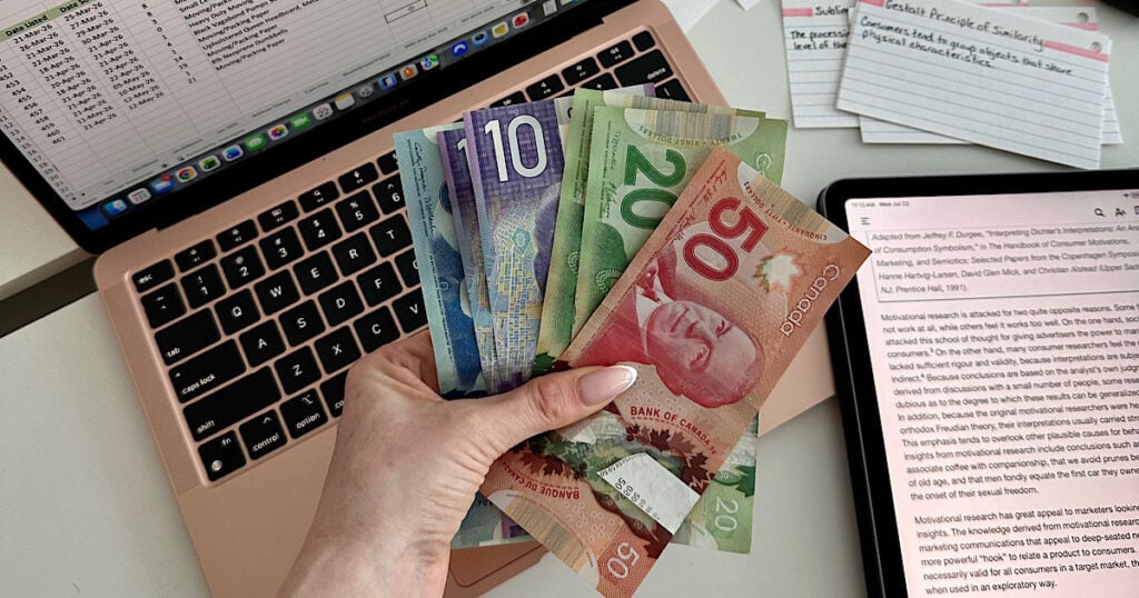 A woman holding a handful of colorful bills.