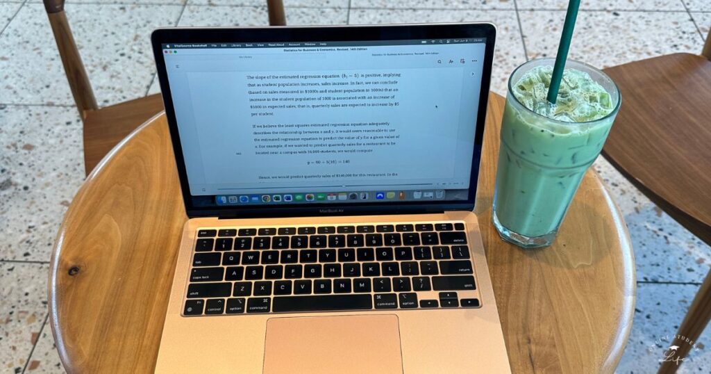 An open laptop and iced matcha on a cafe table.